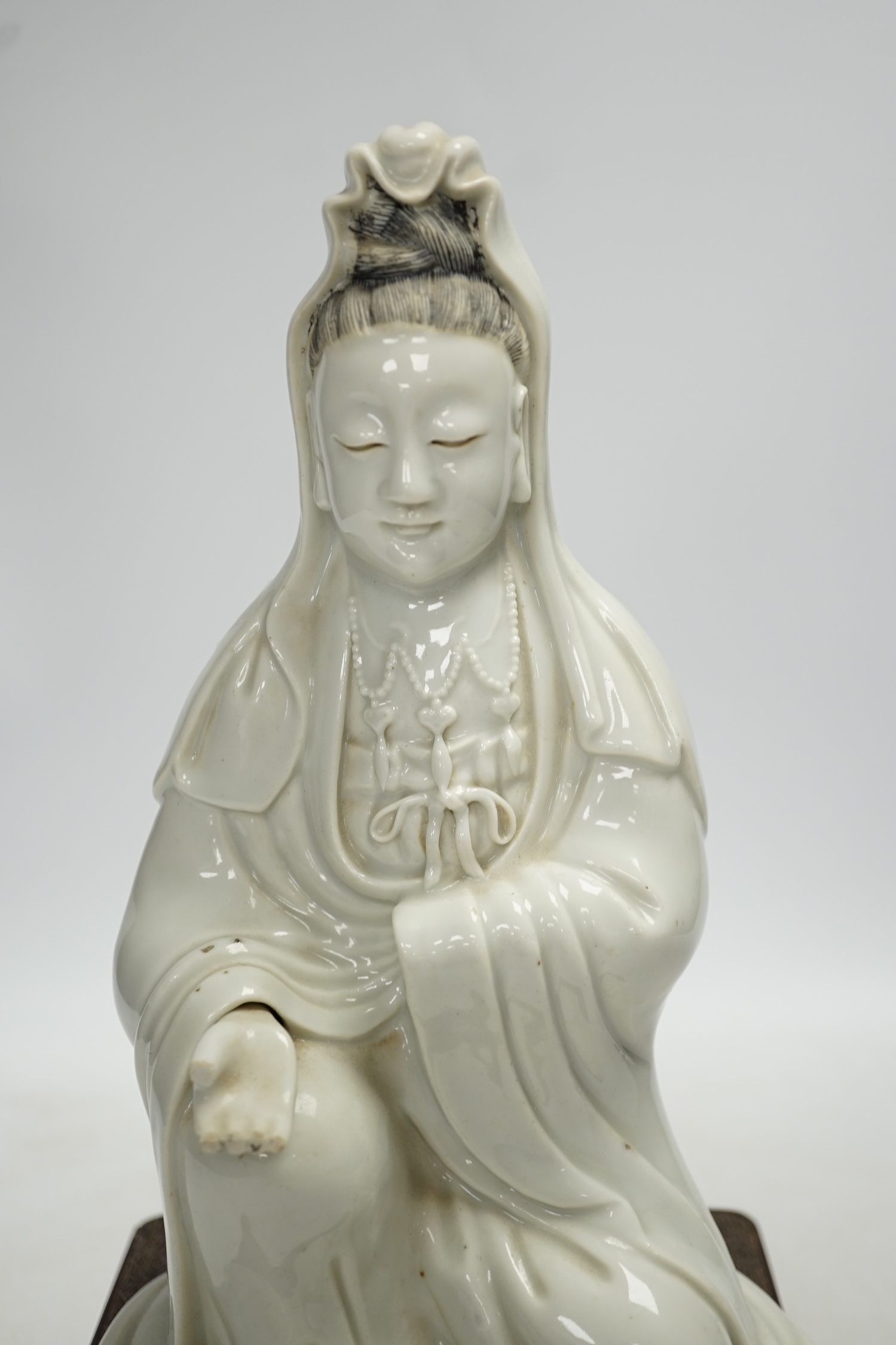 An 18th century Chinese white glazed pottery model of Guanyin on a square hardwood stand, figure 23cm. Condition - poor, hand missing, chips